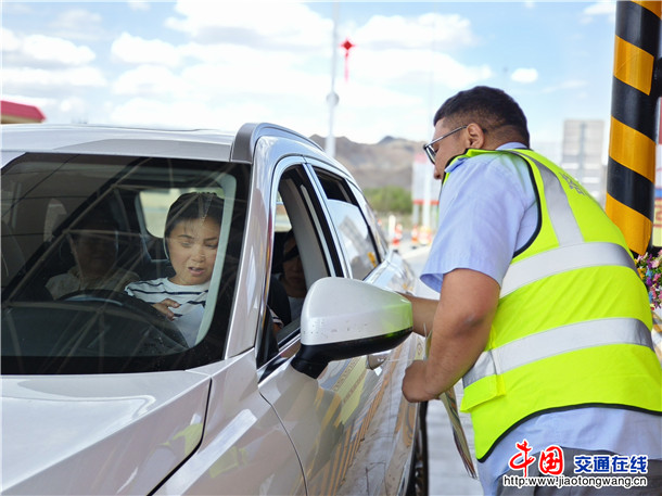 图为：收费站职工为司乘发放宣传单